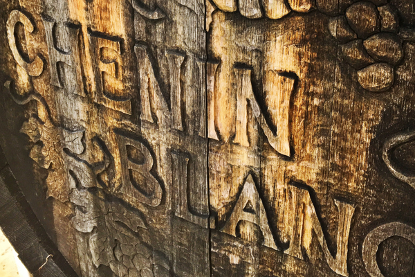 Carved wooden sign reading "CHENIN BLANC" with vine motifs.